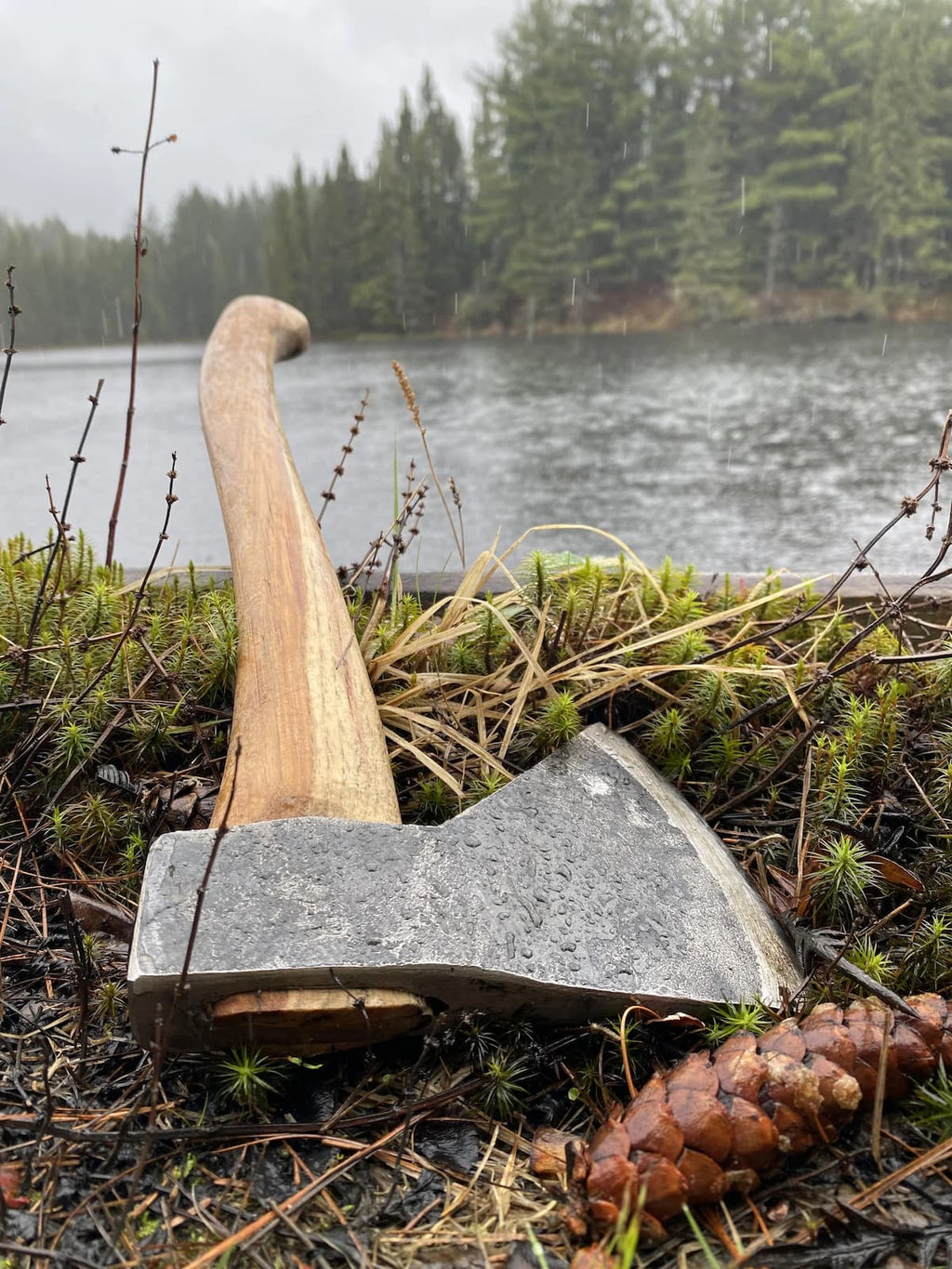 Original Rockaway camping hatchet with hickory handle positioned by lakeside in natural outdoor setting
