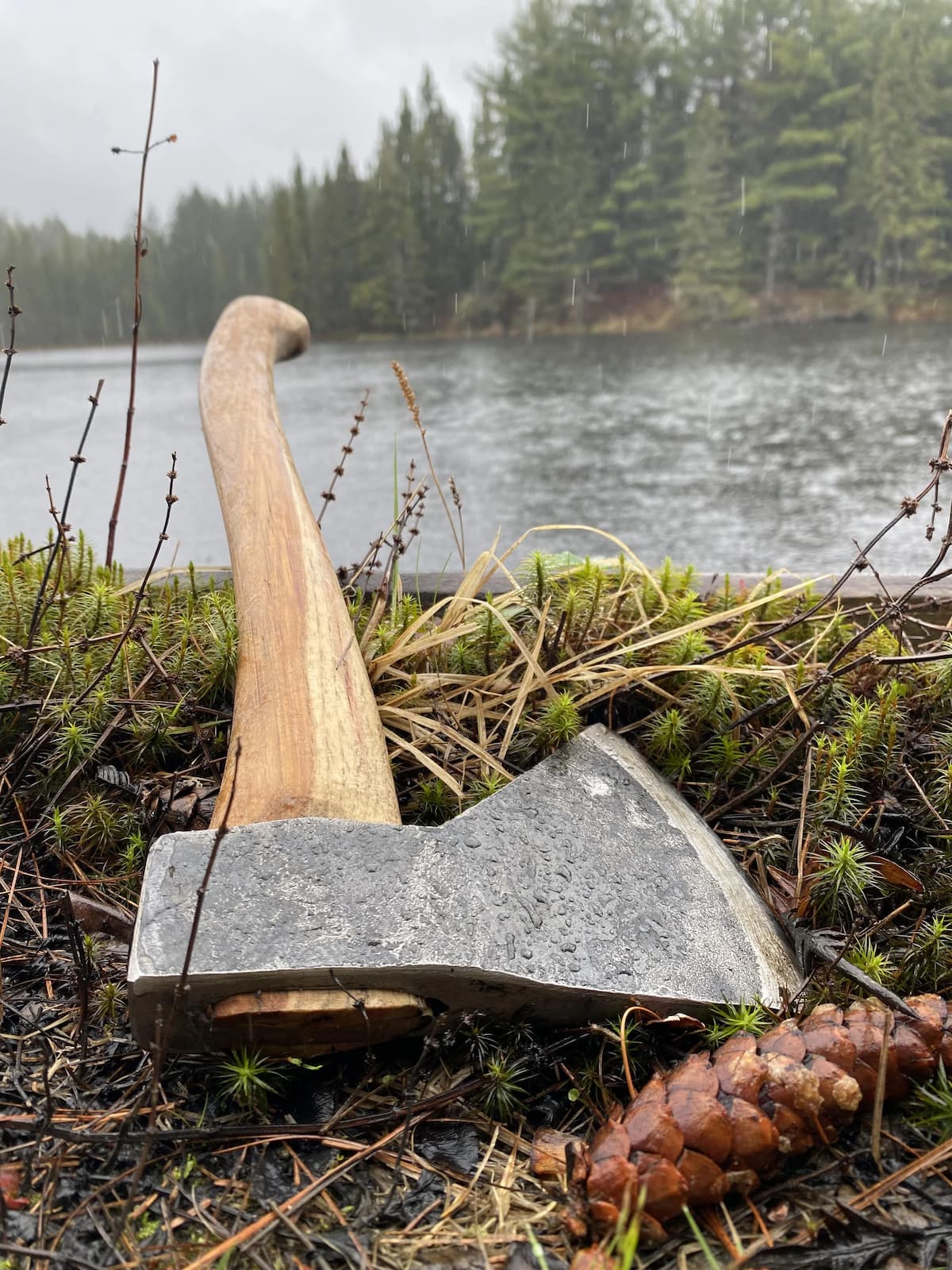 Original Rockaway camping hatchet with hickory handle positioned by lakeside in natural outdoor setting