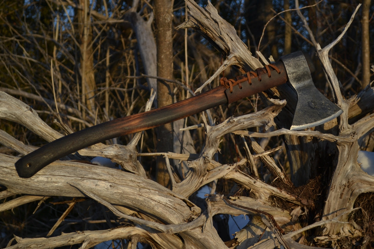 Taiga Moose survival axe with premium hickory handle displayed among natural wood and brush showing bushcraft field use